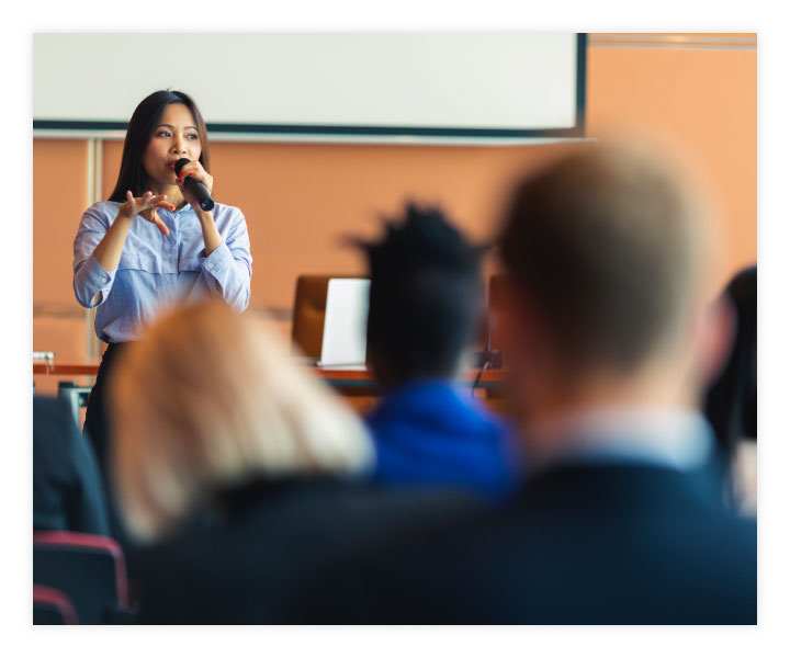 A person in front of a group speaking to an audience