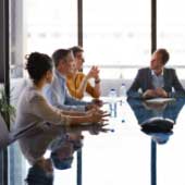Descriptive image of people having a discussion at a conference table to represent how we build strategic partnerships across the public, social and private sectors.