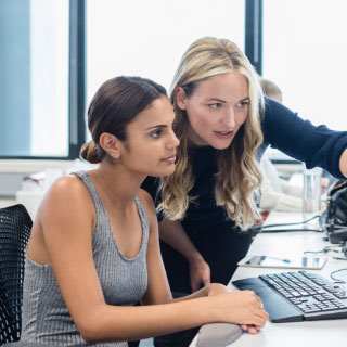 A female instructor teaching another employee.