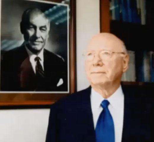 Don Clifton standing in front of a picture of George Gallup