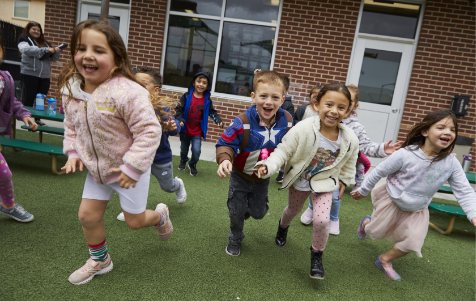 Happy children running outside of school